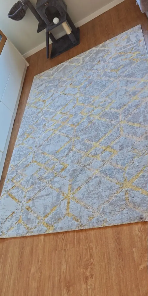 Tapete claro com padrão dourado, acinzentado pela sujidade